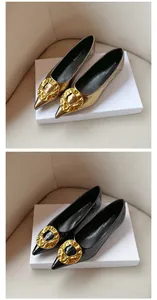 Elegant pointed-toe flat shoes featuring a large artistic gold buckle in black and metallic gold