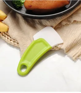 Dettaglio di un raschietto da cucina in silicone verde e bianco per pulire olio e residui
