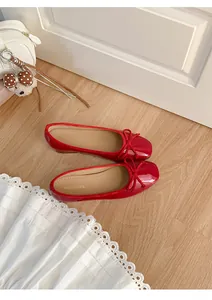 Close-up view of vibrant red ballet flats with delicate bow detail on a wooden floor