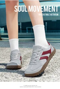 Detailed view of grey and red breathable mesh German trainer sneakers worn on outdoor ground