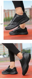 Side detail view of lightweight black mesh running shoes on a red athletic track