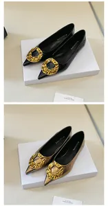 Close-up of elegant pointed-toe flats with hammered gold buckle in black and metallic