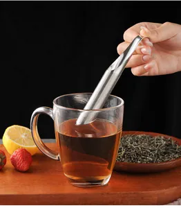 Close-up detail of stainless steel pipe tea infuser being used with a clear glass mug