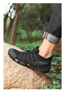 Détail d'une chaussure de randonnée en maille noire respirante sur un terrain rocheux extérieur
