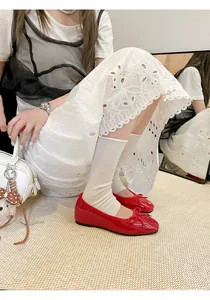 Elegant red patent leather ballet flats with bow detail on model in white lace dress