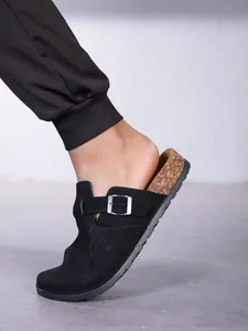 Gros plan détaillé de sabots noirs de style Birkenstock avec semelle en liège au pied.