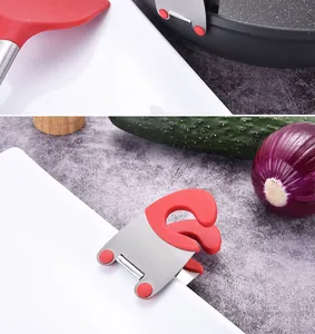 Detail shot of red silicone stainless steel pot edge clip holding a kitchen spatula.