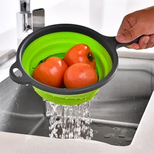 Colino rotondo pieghevole verde con manico per lavare frutta e verdura nel lavandino.