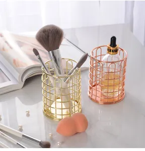 Detailansicht von vergoldeten und roségoldenen Make-up-Pinselhaltern aus Metalldraht auf Tisch