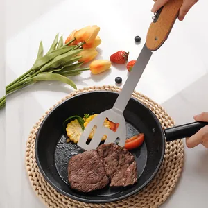Multi-functional stainless steel folding BBQ spatula with wooden handle cooking steak in pan.