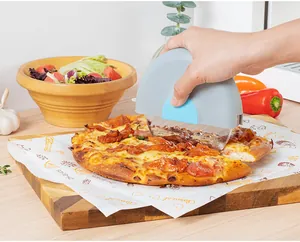 Nahaufnahme eines Edelstahl-Pizzaschneiders, der eine Pizza auf einem Brett schneidet