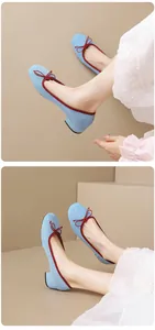 Detailed close-up view of light blue suede ballet flats featuring a red trim and bow accent.