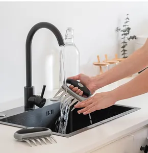 Stainless steel meat shredder claws being washed under a modern black kitchen faucet.
