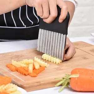 Tagliapatate ondulato per affettare patate e carote su un tagliere in legno naturale