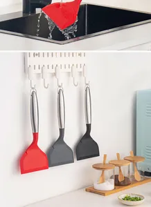Detail showing silicone spatulas with stainless steel handles hung on a kitchen wall organizer