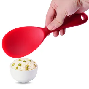 Durable red non-stick silicone rice paddle held over a small white bowl of steamed rice
