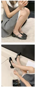 Detailed view of black French Mary Jane heels with rhinestone straps and block heels.
