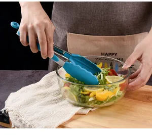 Close-up of 9-inch heat-resistant silicone food tongs serving salad in a glass bowl