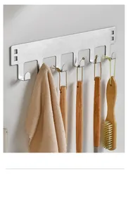 Stainless steel wall-mounted hook rack holding various kitchen brushes and a towel