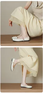Close-up of cream pleated round toe Mary Jane flats with gold studs and bow detail