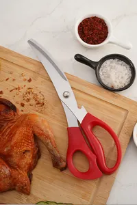 Close-up detail of multi-functional red stainless steel kitchen scissors on a wood board