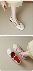 Close-up view of pleated cream Mary Jane flats with decorative bow and gold rivets