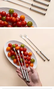 Detailed view of long-handled stainless steel dessert forks held over a fruit plate