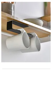 Under cabinet black metal mug holder rack with two white ceramic cups in a kitchen setting