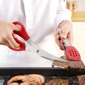 Multifunctional stainless steel kitchen scissors cutting steak on a professional griddle