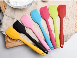 Collection of seven vibrant silicone baking spatulas arranged on a rustic wooden board