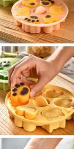 Vue détaillée d'une main retirant un gâteau en forme de patte d'un moule en silicone jaune