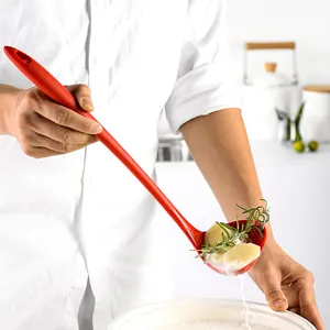 Red long handle heat-resistant silicone soup ladle in professional kitchen setting