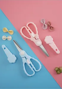 Detalle de tijeras para comida de bebé en acero rosa y azul con tapas protectoras florales.