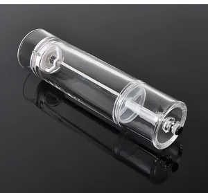 Transparent acrylic cylindrical manual pepper grinder on reflective black background