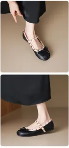 Close-up of black Mary Jane flats with decorative studs and a delicate bow detail