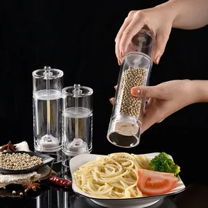 Clear acrylic manual pepper grinder mill shown being used over a pasta dish