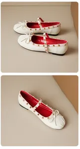Close-up of cream Mary Jane flats with gold studs and bow detail on a neutral base