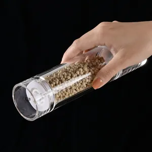 Professional transparent acrylic manual pepper and spice grinder held in hand over black background