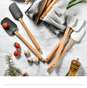 Detailed view of silicone spatulas and brush set with natural wooden handles on marble