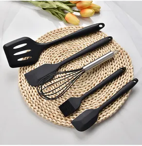 Top view of a 5-piece black heat-resistant silicone kitchen utensil set on a straw mat