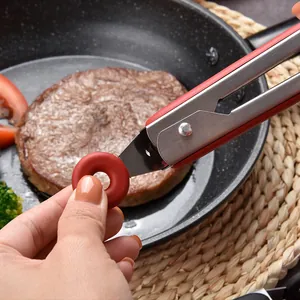 Close-up of stainless steel food tongs with red silicone handle for kitchen cooking