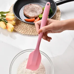 Heat resistant pink silicone baking spatula shown in a professional kitchen scenario