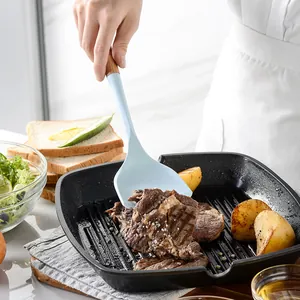Morandi blue silicone spatula with wooden handle used for grilling steak in a pan.