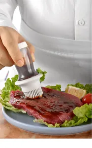 Pinceau à bouteille d'huile en silicone appliquant de la sauce sur un steak cru