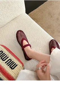 Detail macro view of burgundy mesh Mary Jane flats with rhinestone accents and buckle strap.