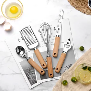 Ensemble d'ustensiles de cuisine avec manches en bois et têtes en acier sur marbre