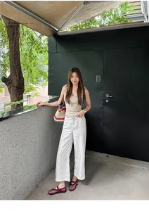 Red mesh Mary Jane flats shown on model with white pants in outdoor lifestyle setting.