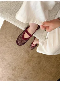 Close-up of burgundy mesh Mary Jane flats with rhinestones on a textured rug.
