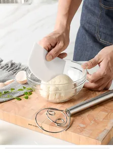 Action shot of using a white scraper and stainless steel Danish dough whisk for bread making