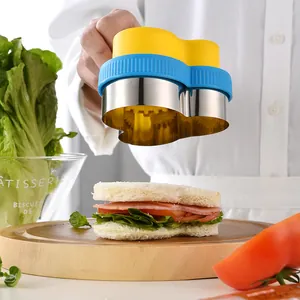 Heart-shaped sandwich cutter mold being used to press a ham and lettuce sandwich